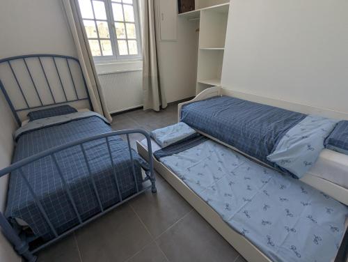 a bedroom with two beds and a window at La Bonne Ecole in Les Landes-Génusson