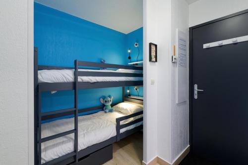 Cette chambre dispose de 2 lits superposés et d'un mur bleu. dans l'établissement Au bon endroit N4 - Studio avec coin montagne 2 à 4 personnes - proche pistes - Belle vue, à Orcières