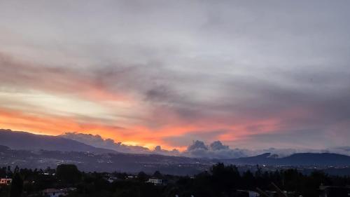 a cloudy sky at sunset with mountains in the background at La Cuadra - Hospedaje en Puembo in Puembo
