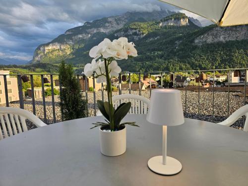 a table with a lamp and white flowers on it at Premium Apartments - central & historical in Meiringen