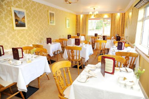 uma sala de jantar com mesas brancas e cadeiras amarelas em Ashville House em Killarney