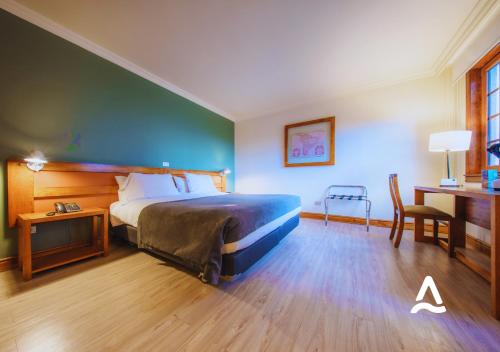 a bedroom with a bed and a table and a desk at Almasur Punta Arenas in Punta Arenas
