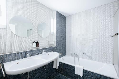 La salle de bains est pourvue d'un lavabo, d'une baignoire et d'un miroir. dans l'établissement Hotel zwölf87, à Ravensbourg
