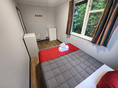a small bedroom with a bed and a window at Pinewood Lodge in Queenstown