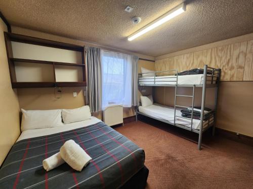 a bedroom with a bed and bunk beds in it at Pinewood Lodge in Queenstown