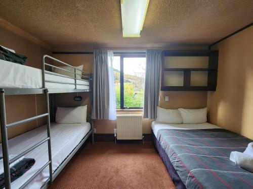 two bunk beds in a room with a window at Pinewood Lodge in Queenstown