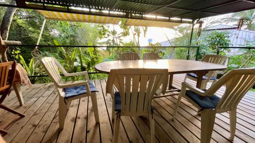 a wooden deck with a wooden table and chairs at Location gîte bungalow à 70m de la plage in Bouillante