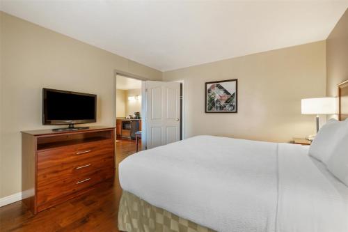 a bedroom with a large bed and a flat screen tv at Best Western Plus John Jay Inn & Suites in Palmdale