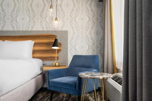 a bedroom with a bed and a blue chair and a table at Aiden by Best Western St George in St. George