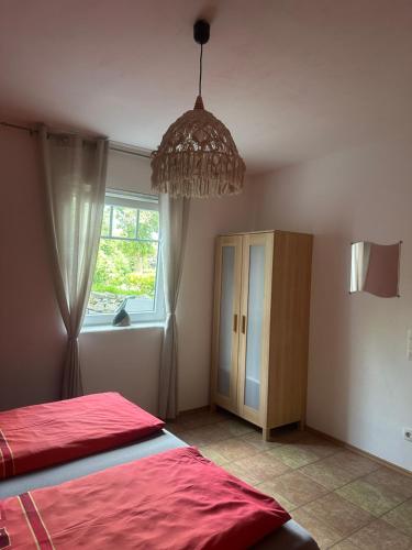 a bedroom with a red bed and a chandelier at Ferienwohnung am Nurburgring in Welcherath