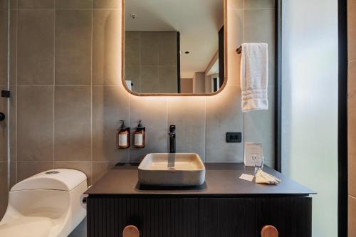 a bathroom with a sink and a toilet and a mirror at Seissta Medellín in Medellín