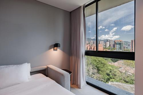 a hotel room with a bed and a large window at Seissta Medellín in Medellín