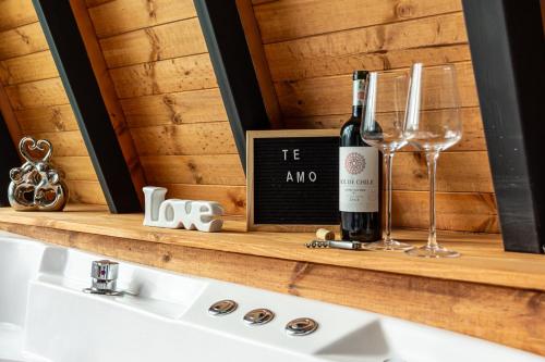 a bottle of wine and glasses on a shelf at Cabañas El Edén in Chía