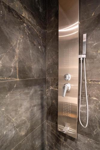 a shower in a bathroom with black marble at Kalon Gaia NOSTOS in Karistos