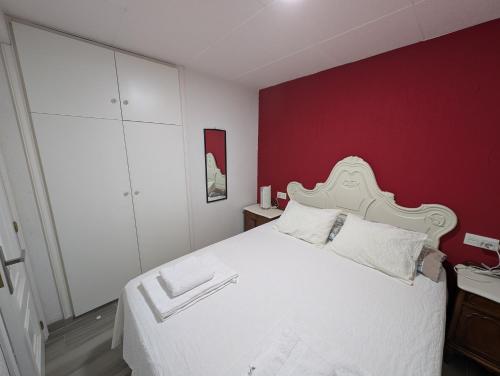 a bedroom with a white bed with a red wall at Olladas de Laxe Apartamento con vistas in Laxe