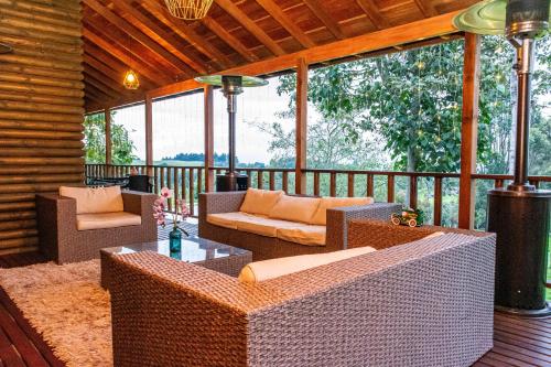 a screened in porch with wicker furniture on a deck at Cabañas El Edén in Chía
