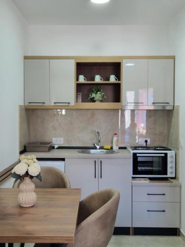 a kitchen with white cabinets and a table with chairs at Apartmani Nataly M2 in Veliko Gradište