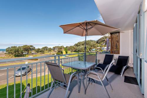 a balcony with a table and chairs and an umbrella at Beachpoint Apartments in Ohope Beach