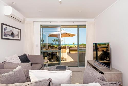 a living room with a couch and a table with an umbrella at Beachpoint Apartments in Ohope Beach