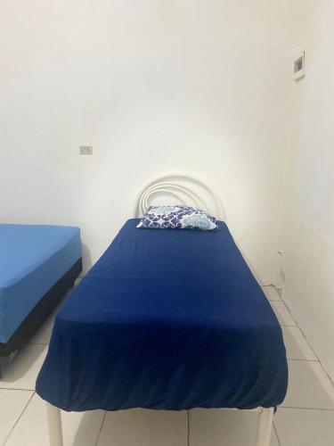 a bed in a room with a blue blanket on it at Espaço de Iguaba Grande in Iguaba Grande