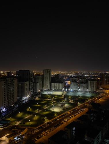 a city lit up at night with a parking lot at Luxury Rooms in Sharjah