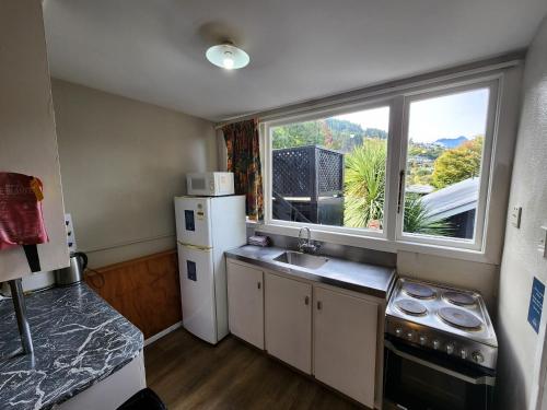 a kitchen with a white refrigerator and a window at Pinewood Lodge in Queenstown