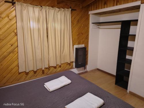Un dormitorio con una cama con dos toallas encima. en La cabaña de Moni, en Dina Huapi