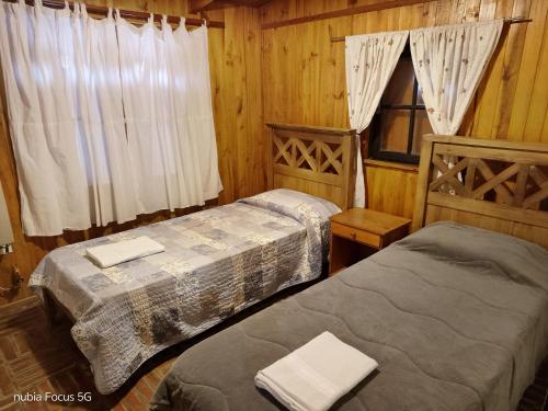 Habitación de madera con 2 camas y ventana en La cabaña de Moni, en Dina Huapi