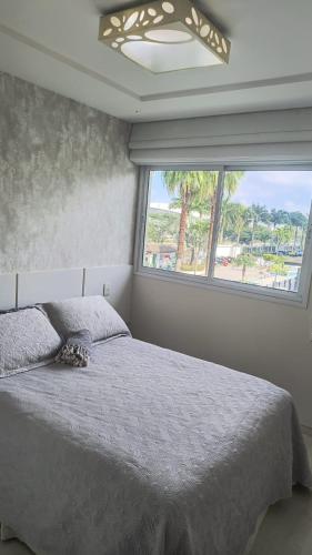 a bedroom with a bed and a large window at Bora Bora Barra Apartments in Rio de Janeiro