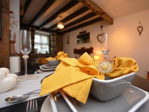 a table with yellow napkins and a bowl on a table at 1 bed property in Trefor Beach 77891 in Llanaelhaiarn