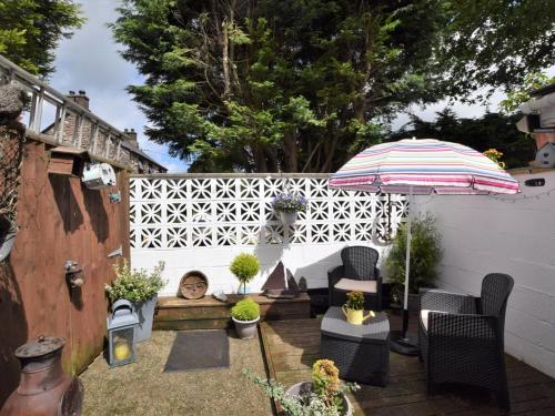 a backyard with a white fence and an umbrella at 1 bed property in Trefor Beach 77891 in Llanaelhaiarn