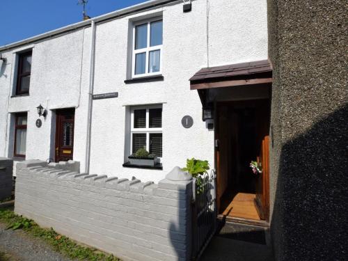 a white house with a brick wall next to a building at 1 bed property in Trefor Beach 77891 in Llanaelhaiarn