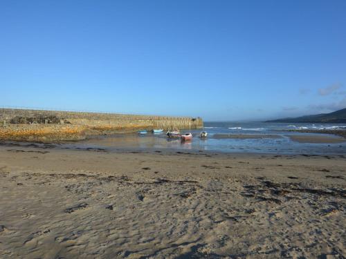 a sandy beach with two boats in the water at 1 bed property in Trefor Beach 77891 in Llanaelhaiarn