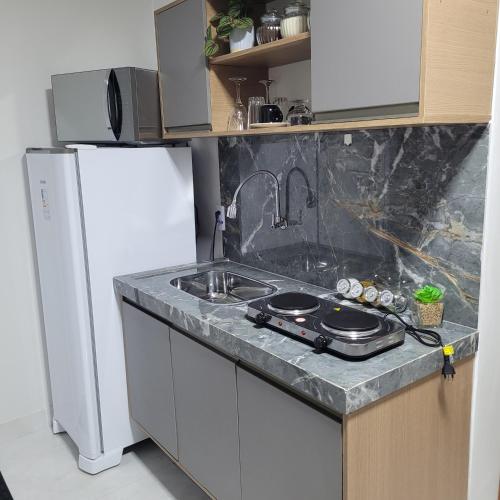 a kitchen with a sink and a refrigerator at Pousada Loft Marabá in Marabá