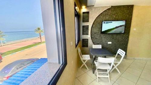 a room with a balcony with a table and a television at Beachfront First floor mekad in Oued Laou