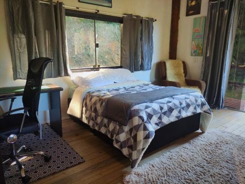 a bedroom with a bed and a desk and a window at Propriedade inteira e Kombi-home em meio à mata in Rancho Queimado