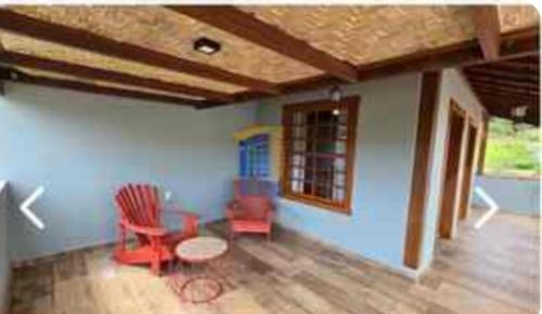 a living room with red chairs and a table at 4 qtos, pisc aquec, jacuzzi, centro bichinho in Bichinho