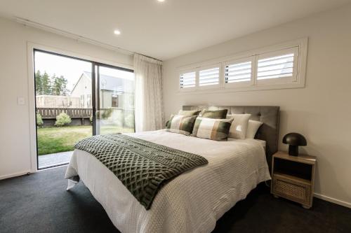 a bedroom with a bed and a large window at Alpine | BBQ & Fireplace | Table Tennis - HS68319 in Hanmer Springs