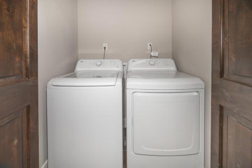 two washing machines in a bathroom next to a door at Mariposa Grove Creekside Retreat in Fish Camp