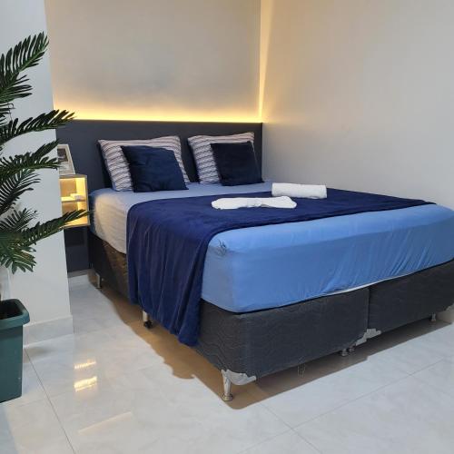 a bedroom with a bed with blue sheets and a christmas tree at Pousada Loft Marabá in Marabá