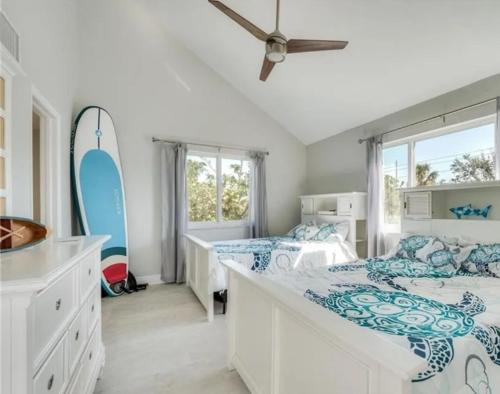 a bedroom with two beds and a surfboard on the wall at Luxury Home with Deeded Private Beach Access Sanibel Island - 28 Day Stay Minumum in Sanibel