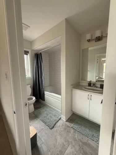 a bathroom with a tub and a toilet and a sink at The Evergreen Escape- Games Nature Near Muskoka in Severn