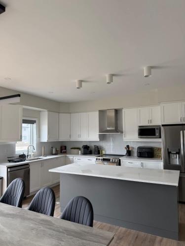 a kitchen with white cabinets and a table and chairs at The Evergreen Escape- Games Nature Near Muskoka in Severn