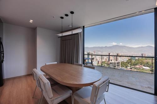 a dining room with a table and chairs and a large window at Seissta Medellín in Medellín