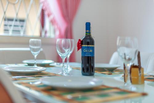 a bottle of wine sitting on a table with glasses at Casa Maison Rosé - Piscina, Lareira e Banheira in Porto Alegre