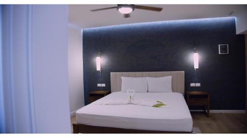 a bedroom with a white bed with a blue wall at Hotel Soficu Green Village 