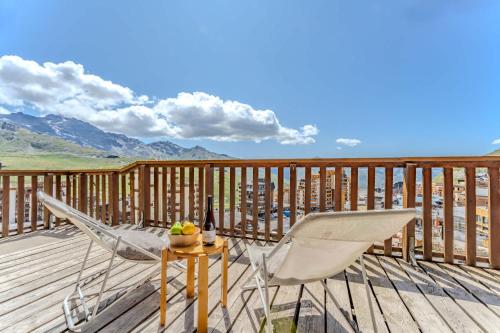 a deck with a table and chairs and a bottle of wine at Cozy Alpine Chalet with Ski-In access and Parking in Val Thorens 10 Niverolles in Val Thorens