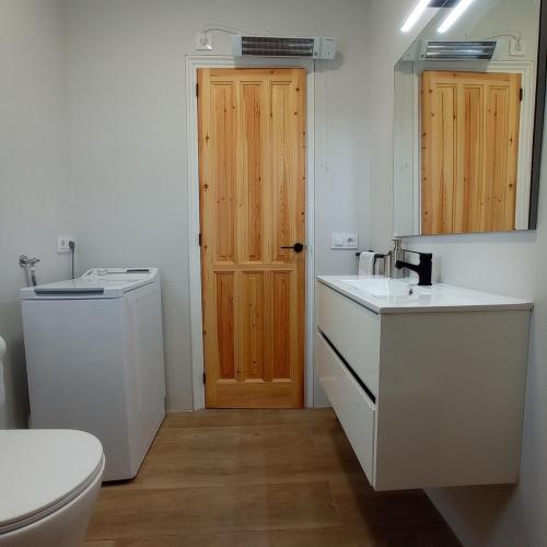 a bathroom with a toilet and a wooden door at Pis a primera línia de mar in L'Escala