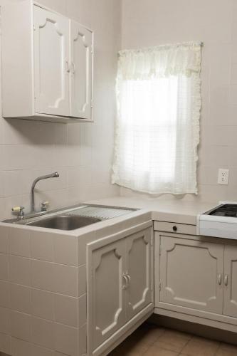 a white kitchen with a sink and a window at COLONIAL Suites in Ciudad Valles