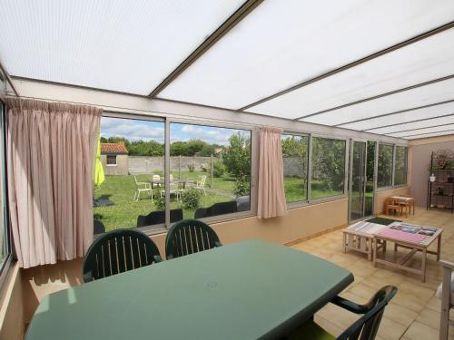 une véranda avec une table et des chaises ainsi qu'une grande fenêtre dans l'établissement Maison rénovée avec jardin clos, 3 chambres, wifi, vélos, proche Réserve du Marais Poitevin - FR-1-426-403, à Saint-Denis-du-Payré